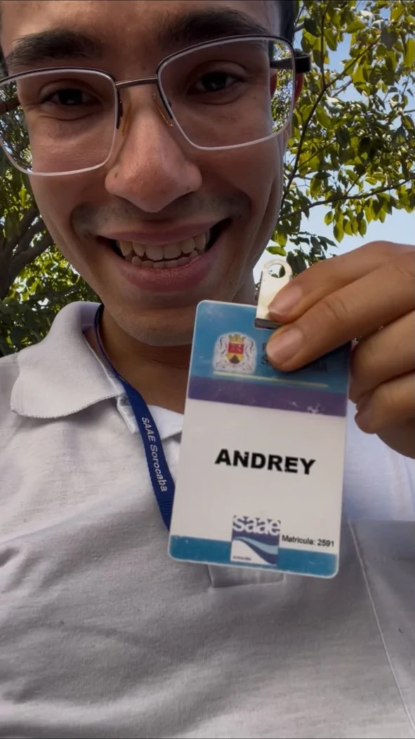 Andrey sorrindo e mostrando o crachá do SAAE Sorocaba, no período como servidor
